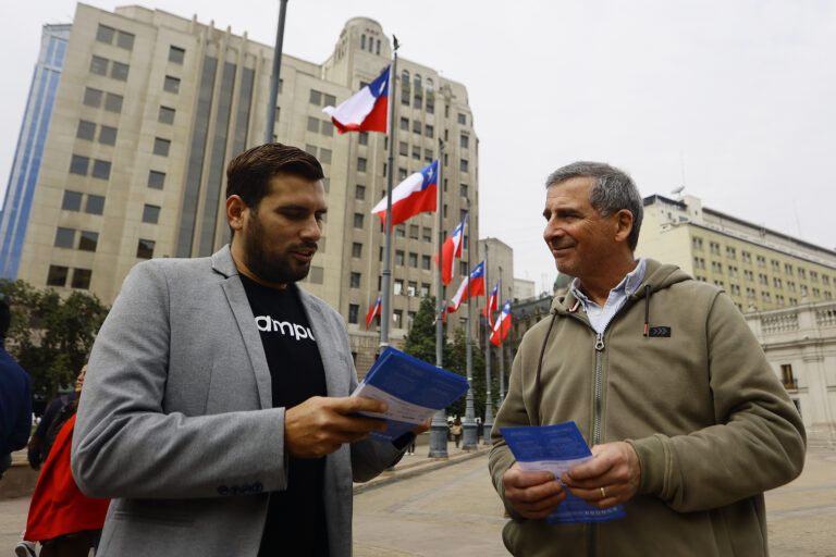 Voluntario entrega folleto informativo sobre proceso de participación.